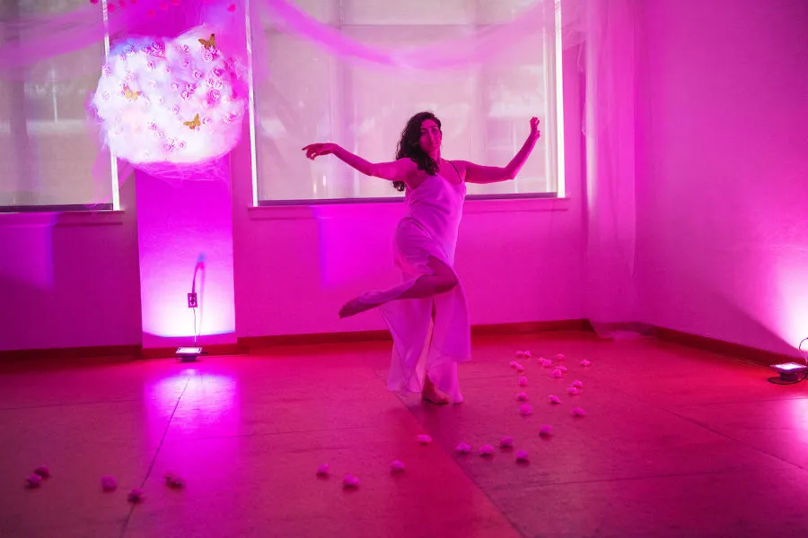 A dancer performs in a magenta room with a white globe