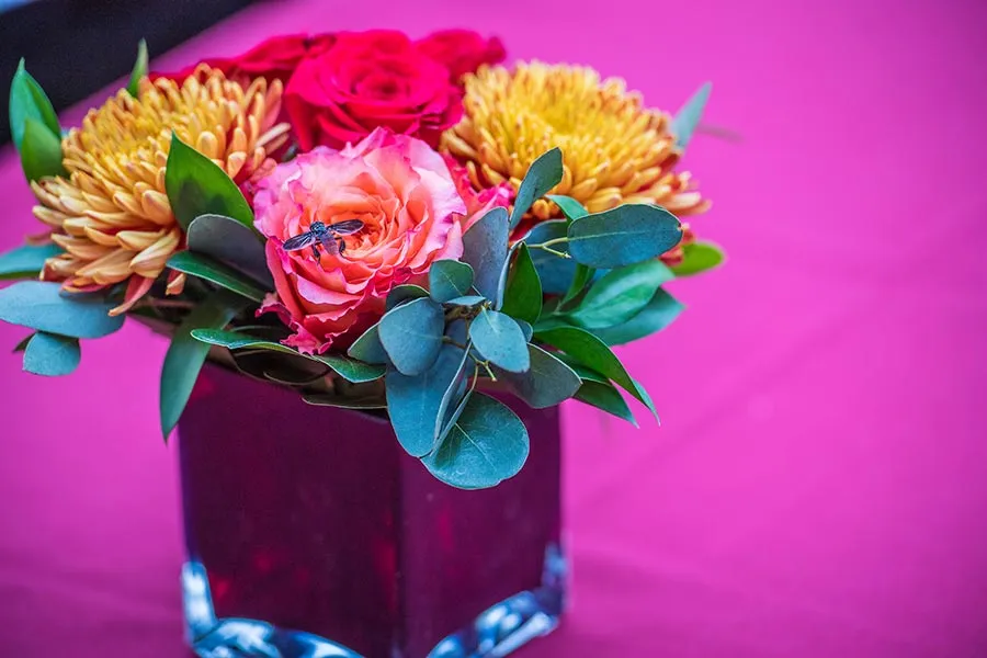 colorful lowers in a square vase on a pink tablecloth