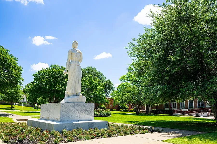 The Minerva statue on TWU Denton campus' Pioneer Circle surrounded by spring flowers on a sunny day