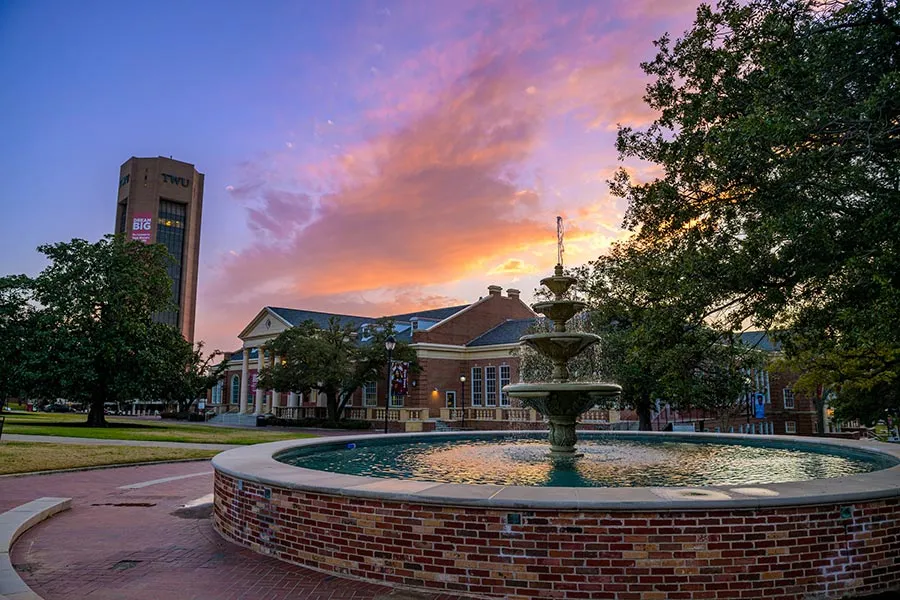 TWU fountain with buildings in background at sunset
