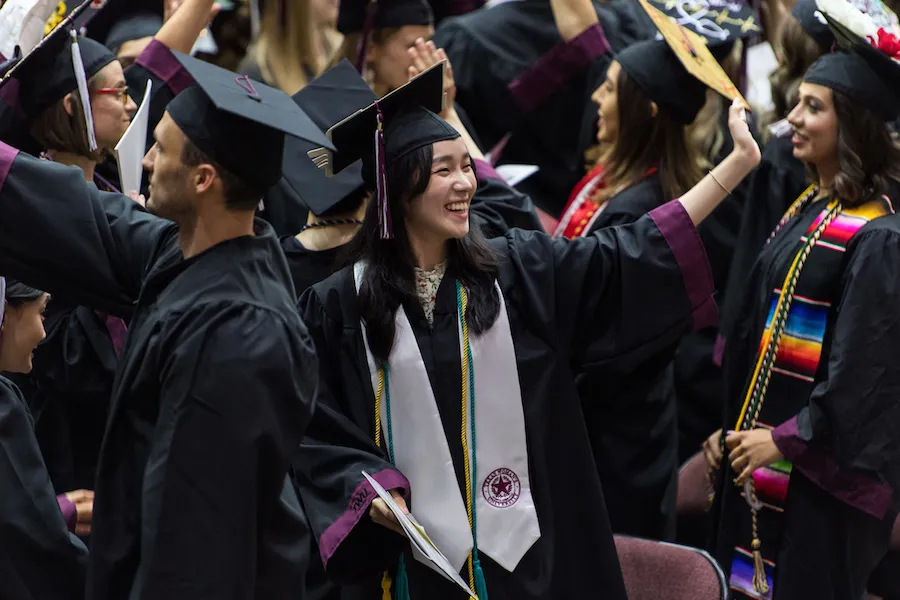 Students wave to family during graduation ceremony.