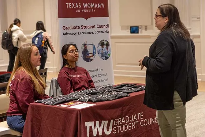 Two TWU students sitting at a table promoting the Graduate Student Council