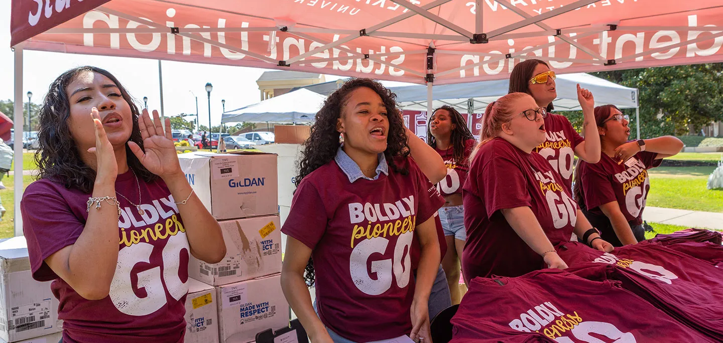 students wearing maroon shirts reading Pioneers Boldy Go