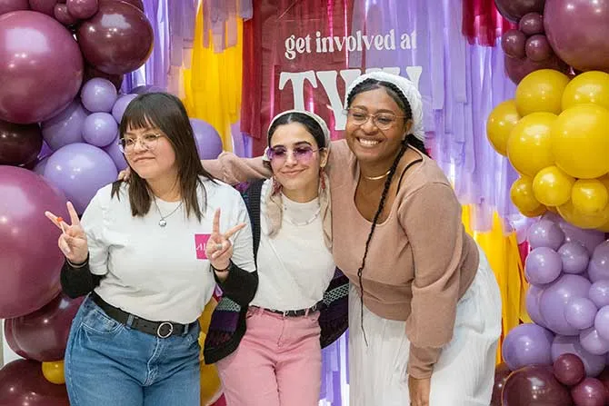 Three TWU students at org fest posing in front of balloons