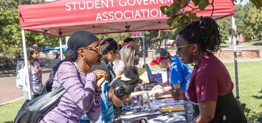 TWU students under tent during the summer sun helping others to register to vote. 