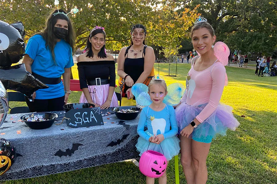 Two girls dressed up as fairies get Halloween candy from the SGA table at the Boo at the U event