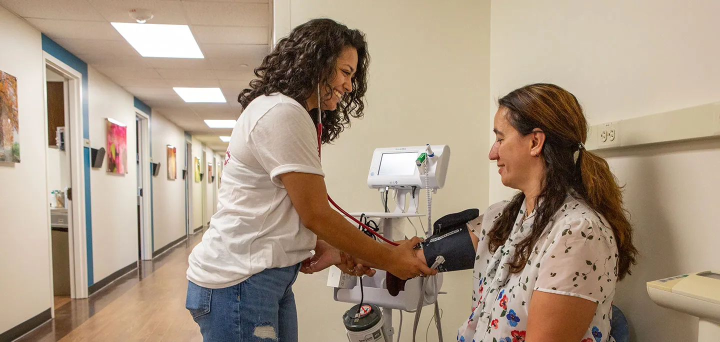 TWU employee and PATH student using blood pressure cuff