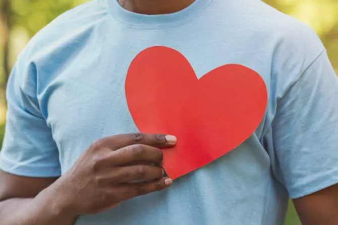 Man holding a heart cutout over his heart