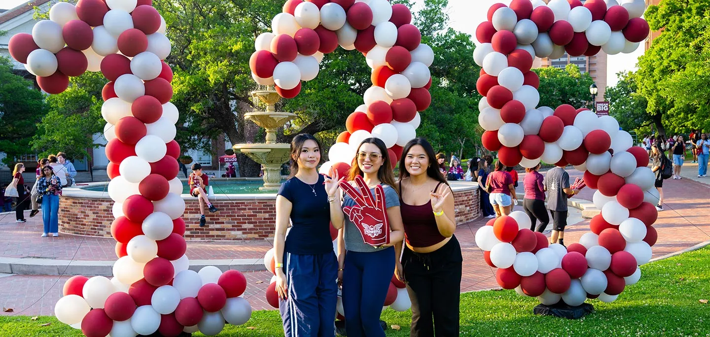 Students standing in front of balloons in the form of 125