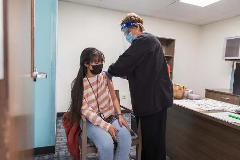 A masked student gets her covid-19 vaccine at the TWU Student Health Center