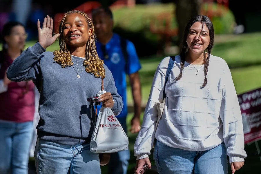 Two female prospective students tour campus on a sunny day