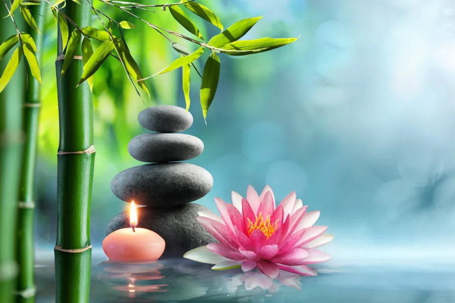 a stack of smooth Zen rocks with a lotus flower and a candle