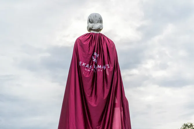 The Pioneer Woman statue from the back, wearing a long cape with the TWU logo on it
