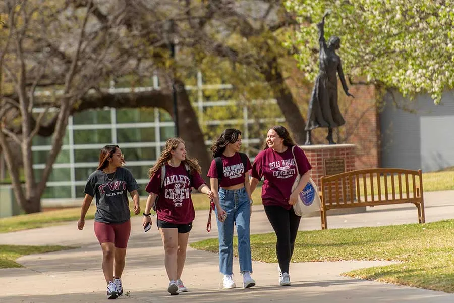 Four TWU students walk across campus on Redbud Lane.