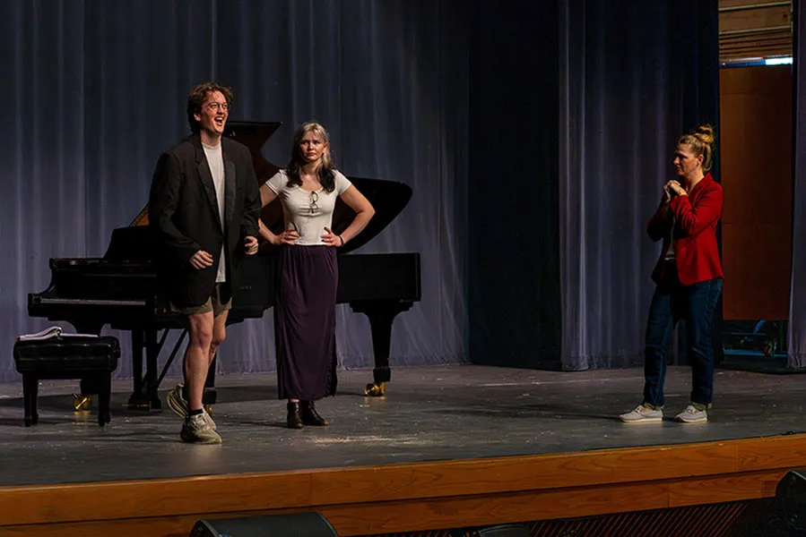 Two actors on stage with the director doing staging.