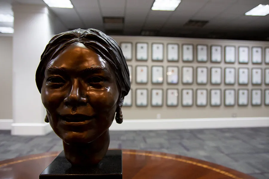 Statue sitting on a table with plaques in the background in the Texas Women's Hall of Fame in the Blagg-Huey Library. 