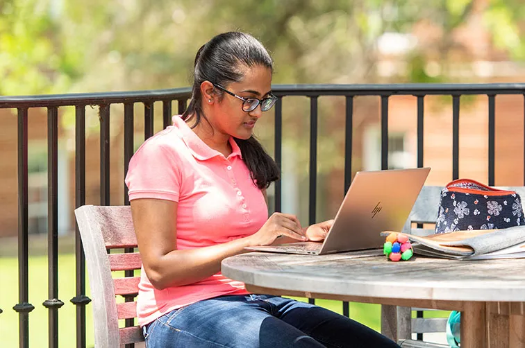 student sitting outside working on a computer