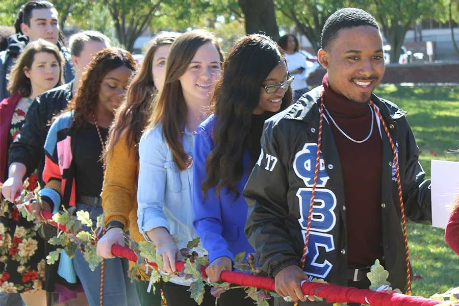 TWU students walk through the Denton campus holding an oak leaf chain.
