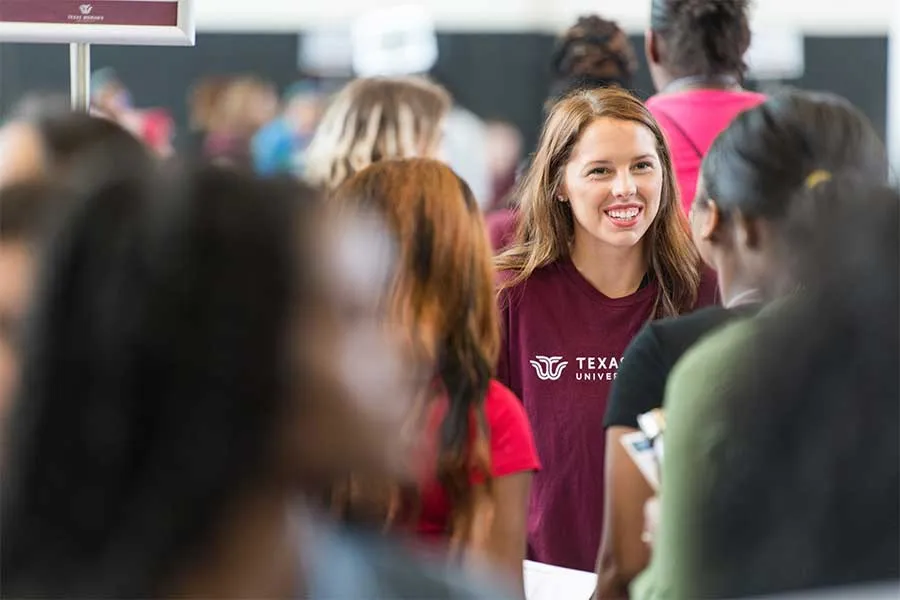 A TWU student is focused on through a crowd at orientation.
