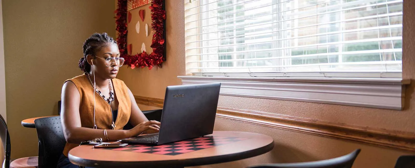A TWU student works at a laptop by a window