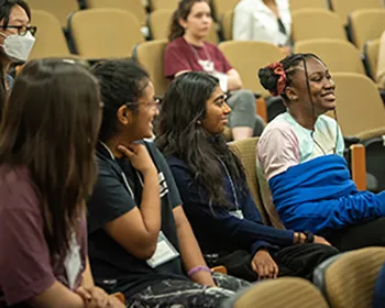 A group of students sit together smiling in a lyceum-style classroom