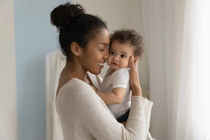 A new mother smiles and holds her newborn baby.