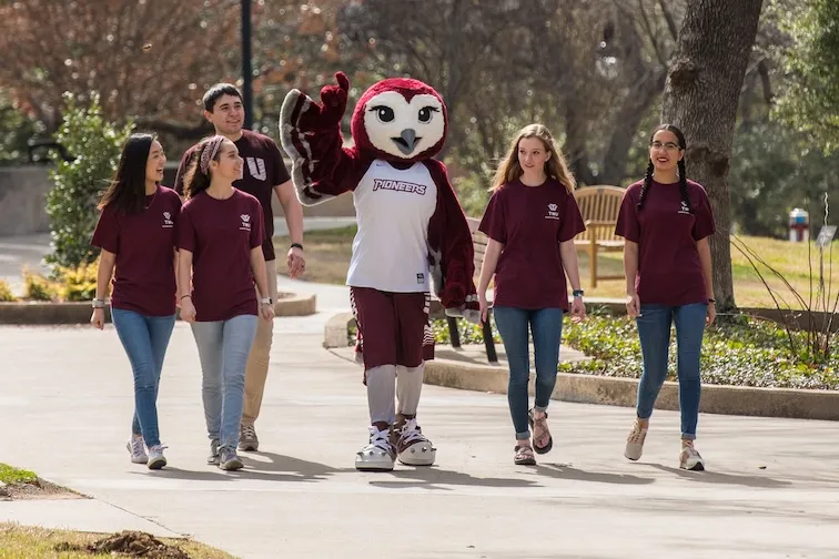 Oakley and Students walking on the Denton Campus.