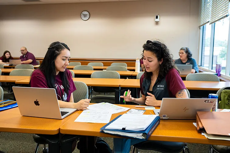 A student meets with her Academic Advisor in a classroom setting.