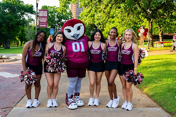 The Pioneer Pride Dance Team poses with Oakley at an on-campus event.