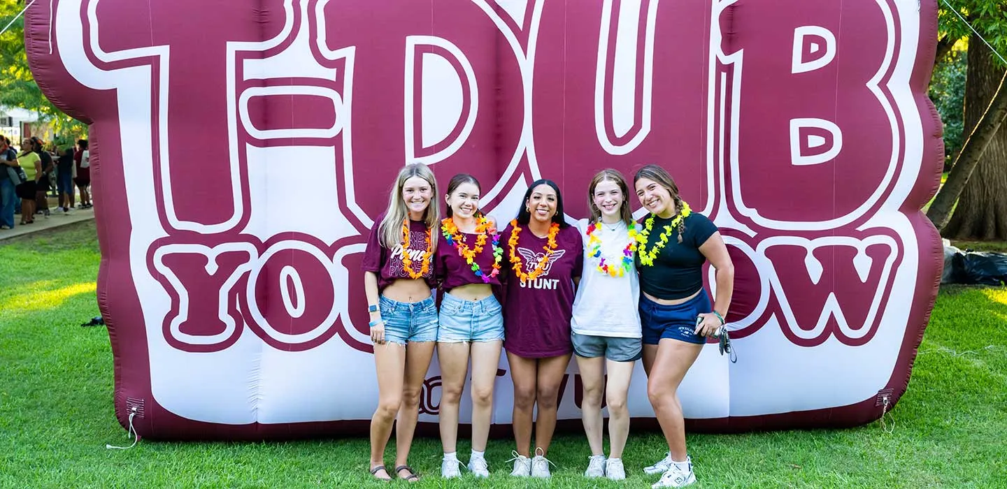 TWU students pose for a photo in front of a giant 