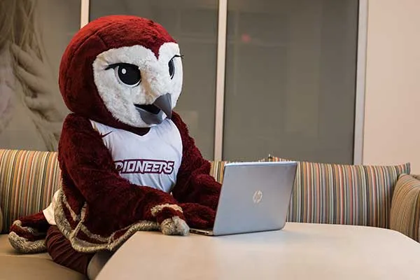 Oakley sits at a desk on a computer