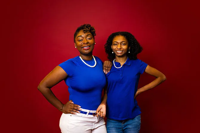 A portrait of a TWU graduate student and her daughter on a maroon background.
