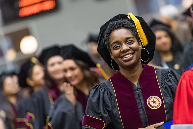 A doctoral graduate in her academic regalia during a commencement ceremony at TWU.