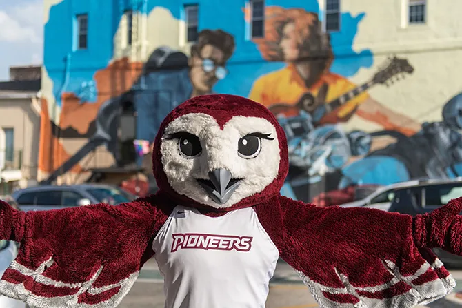 ̽��¥'s mascot, Oakley, poses in front of an iconic Denton square mural.