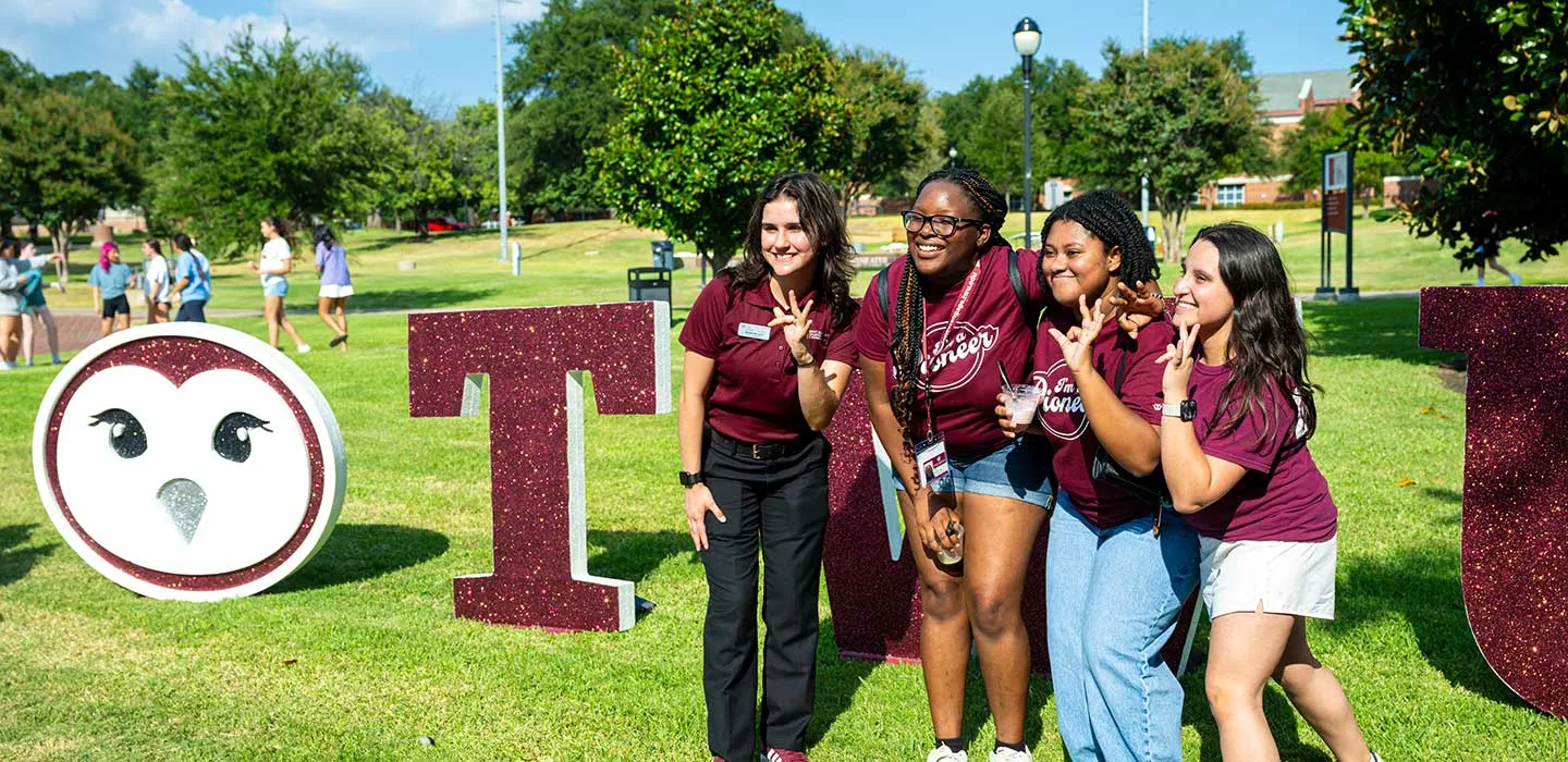 Four TWU students pose for a group photo at an event