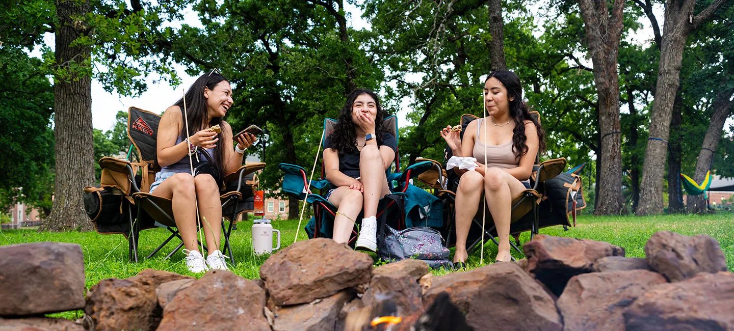 Three TWU students hand out outdoors eatings smores at an on campus event.