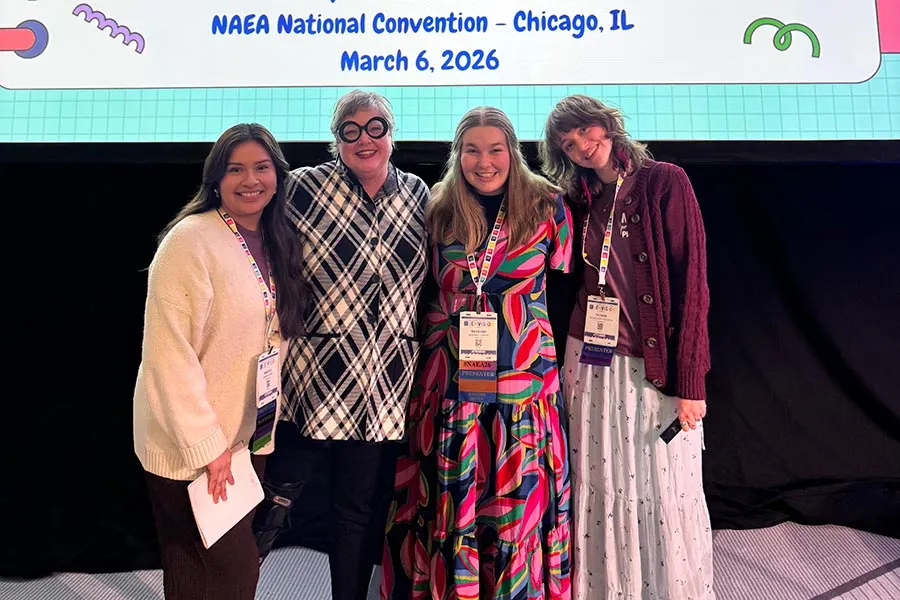 Laura Lee McCartney stands with three ��ݮ��ý�������� students in front of the large display montiro