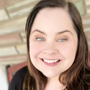 Headshot of Natalie McCurley - smiling white woman with blue eyes and brown hair, wearing a black top