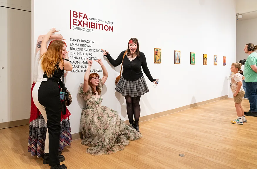 Graduating students point to their names in vinyl, during the Spring 2025 BFA Exhibition.