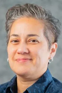 Portrait of cher musico. Smiling, short cropped hair, blur collared shirt