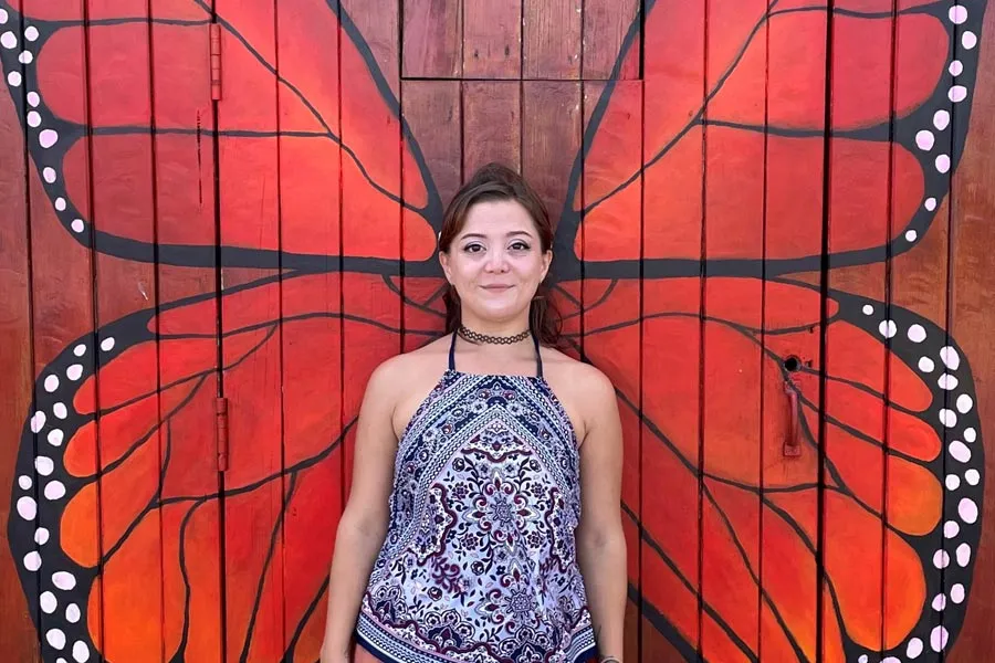 Hannah Werchan standing against a door she painted with wings