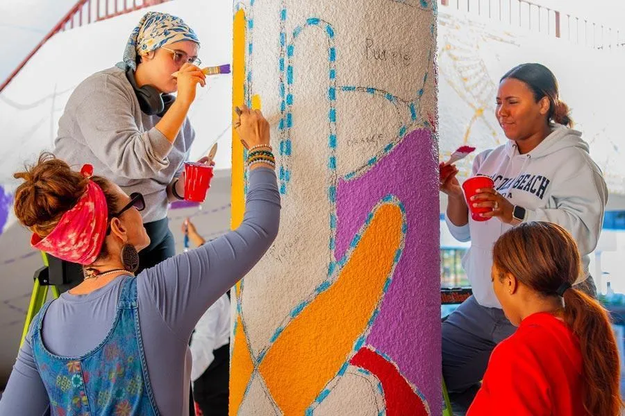Students paint pillar in front of ACT Building for campus mural