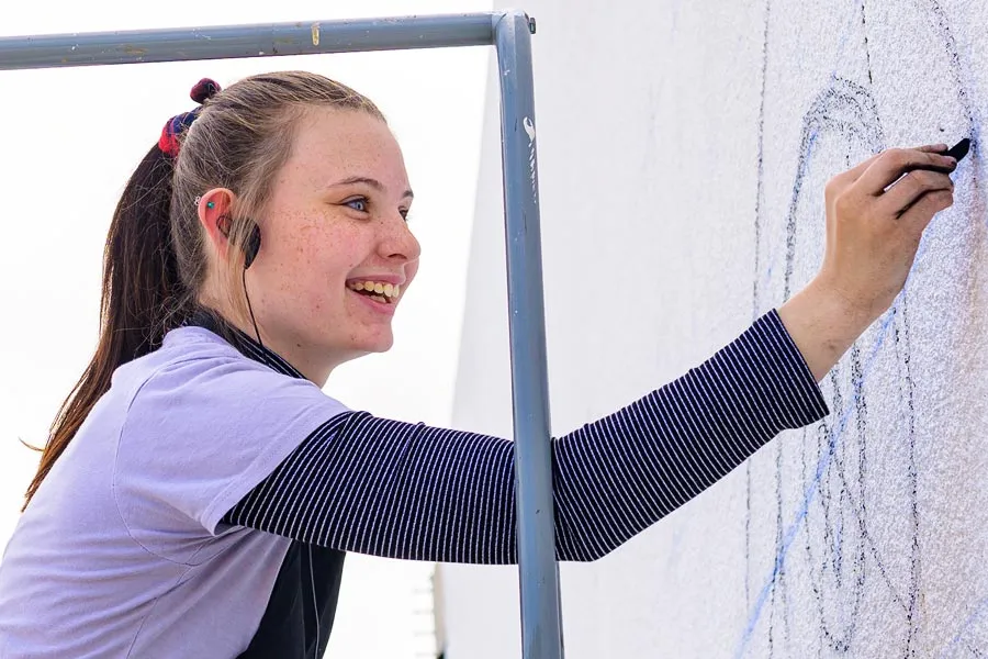 Chloe Selvey works on the mural at the corner of Third and Oakland 