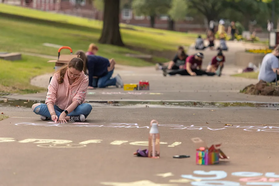 Students chalk affirmations on TWU sidewalks during Make a Difference Day 2021