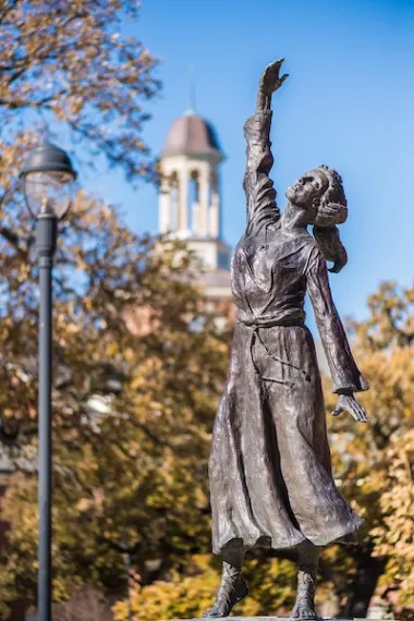 Photo of a campus statue of a girl reaching toward the sky