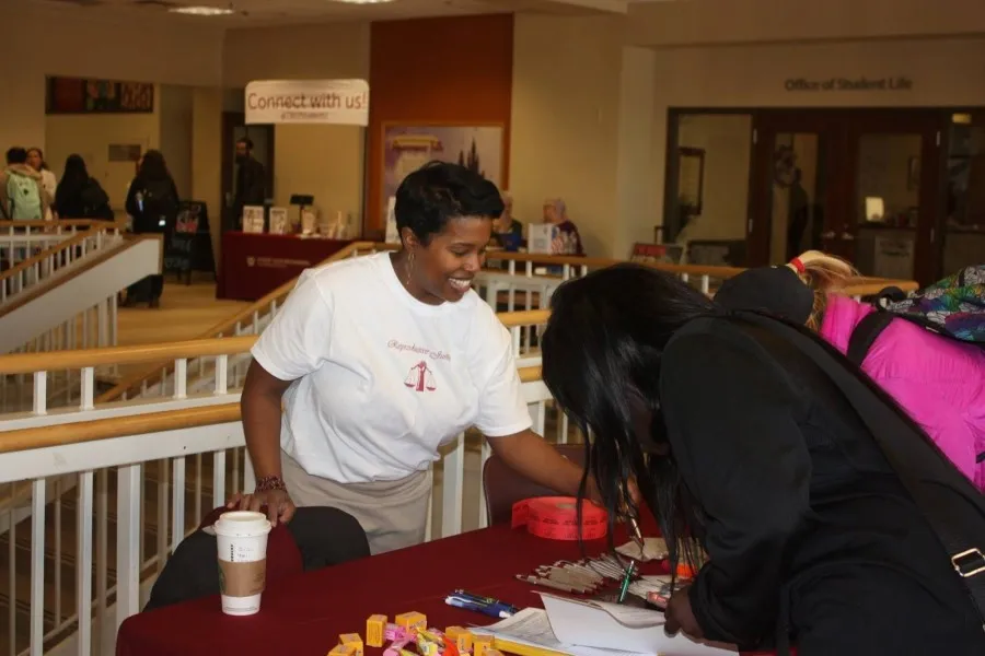 Morgan May, MWGS doctoral student and planning committee member, helps students sign in and enter a door prize drawing at the reproductive justice fair.