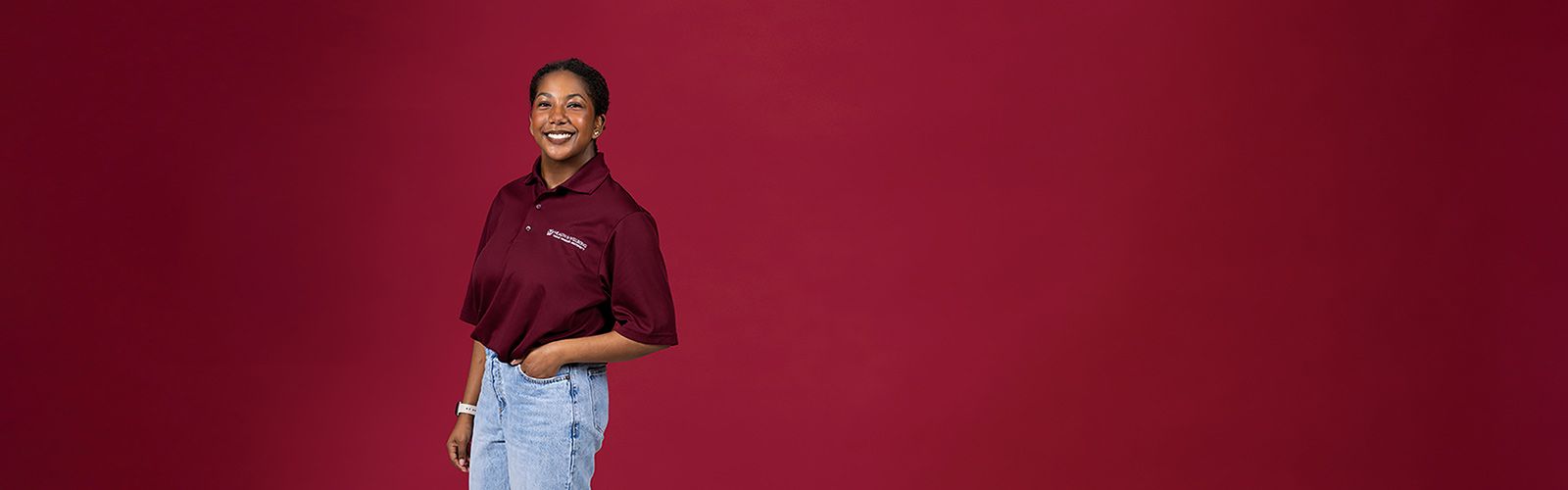 A TWU student wearing jeans and a university branded shirt