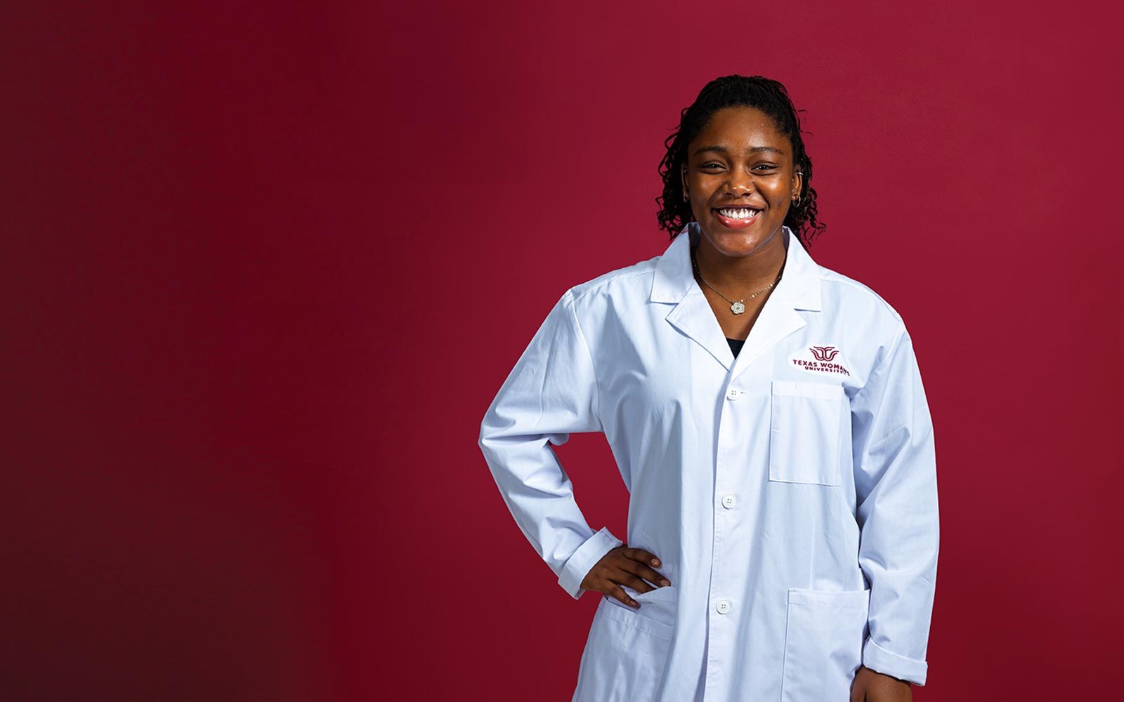 A TWU student wearing a university branded white lab coat