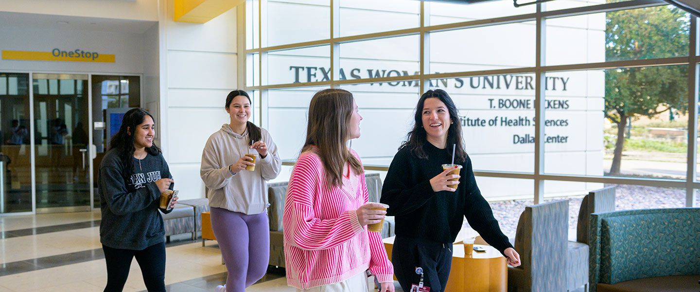 A group of four TWU students walk through the lobby of the Dallas campus.