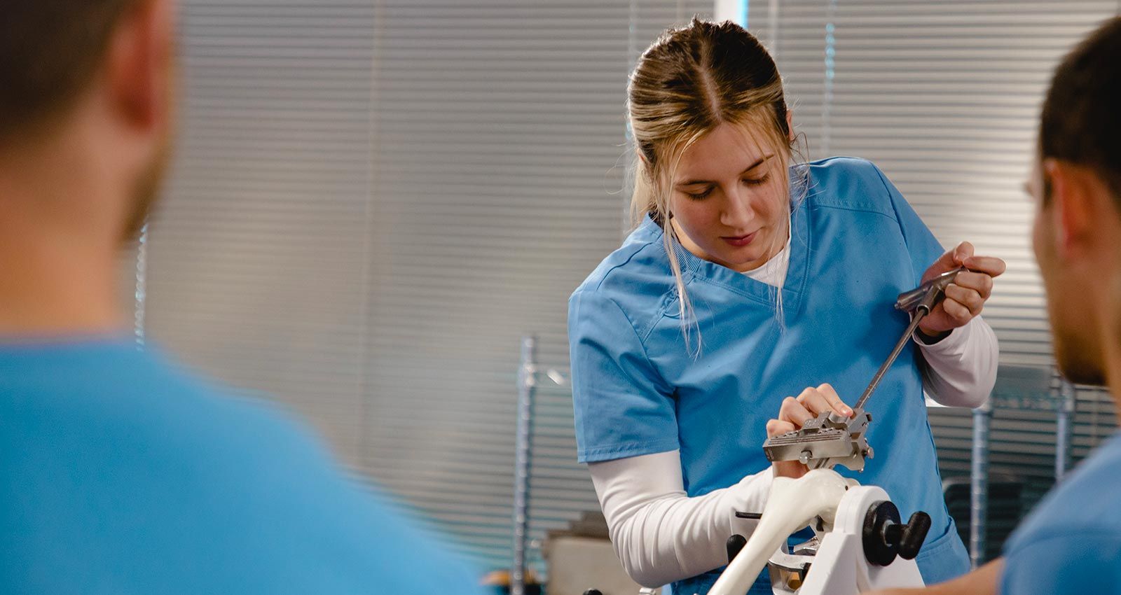 Three people in medical scrubs work with orthopedic devices